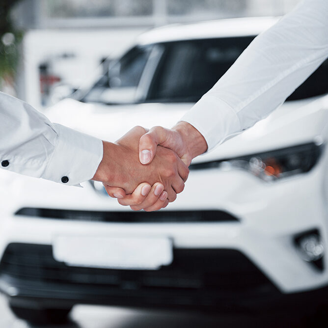 Close up of sales manager in black suit selling the car to the customer.